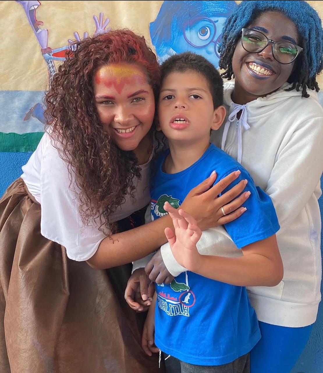Voluntárias do Instituto acolhendo criança em oficina criativa